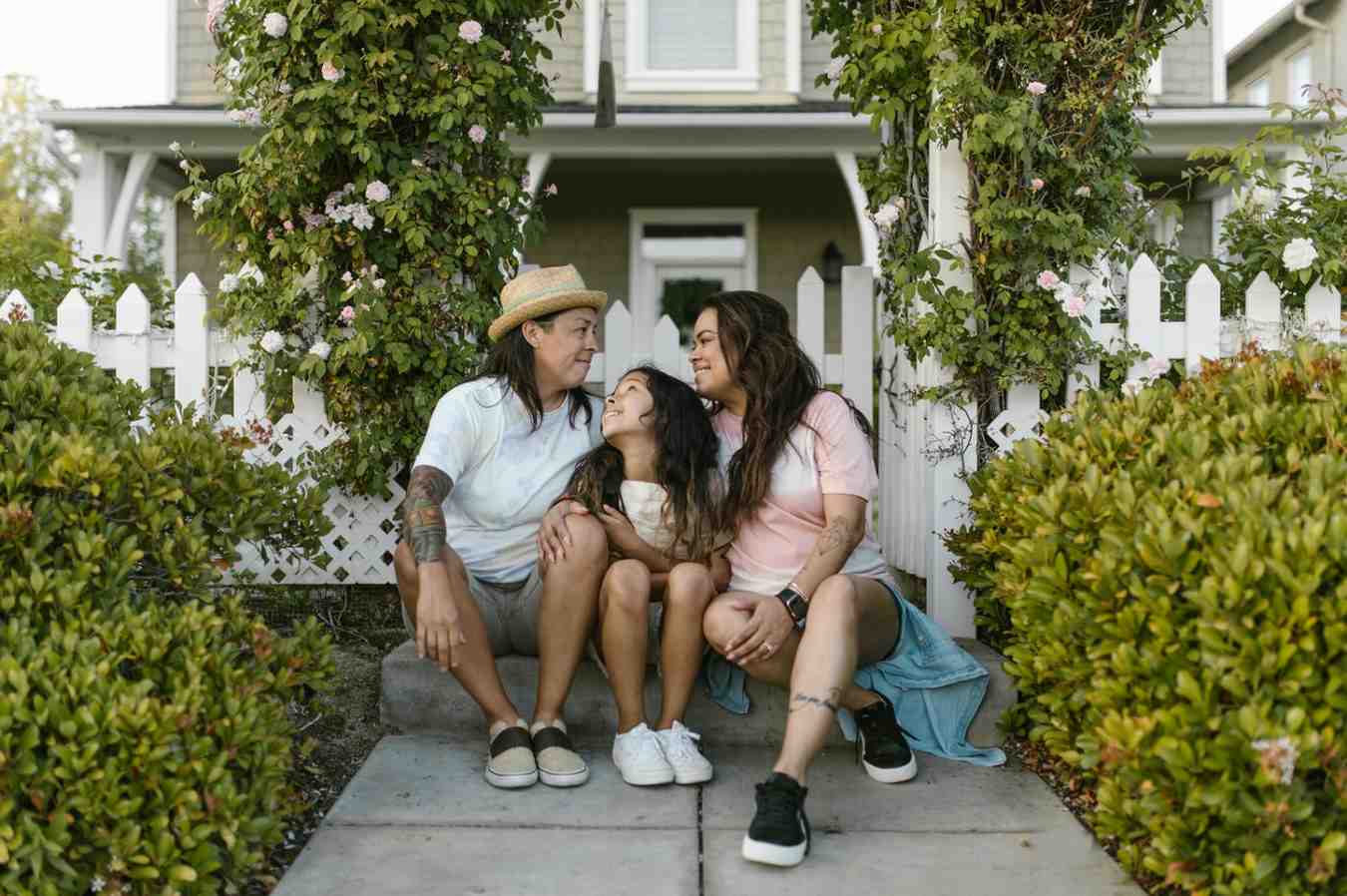 A family standing happily in front of their modern suburban home
